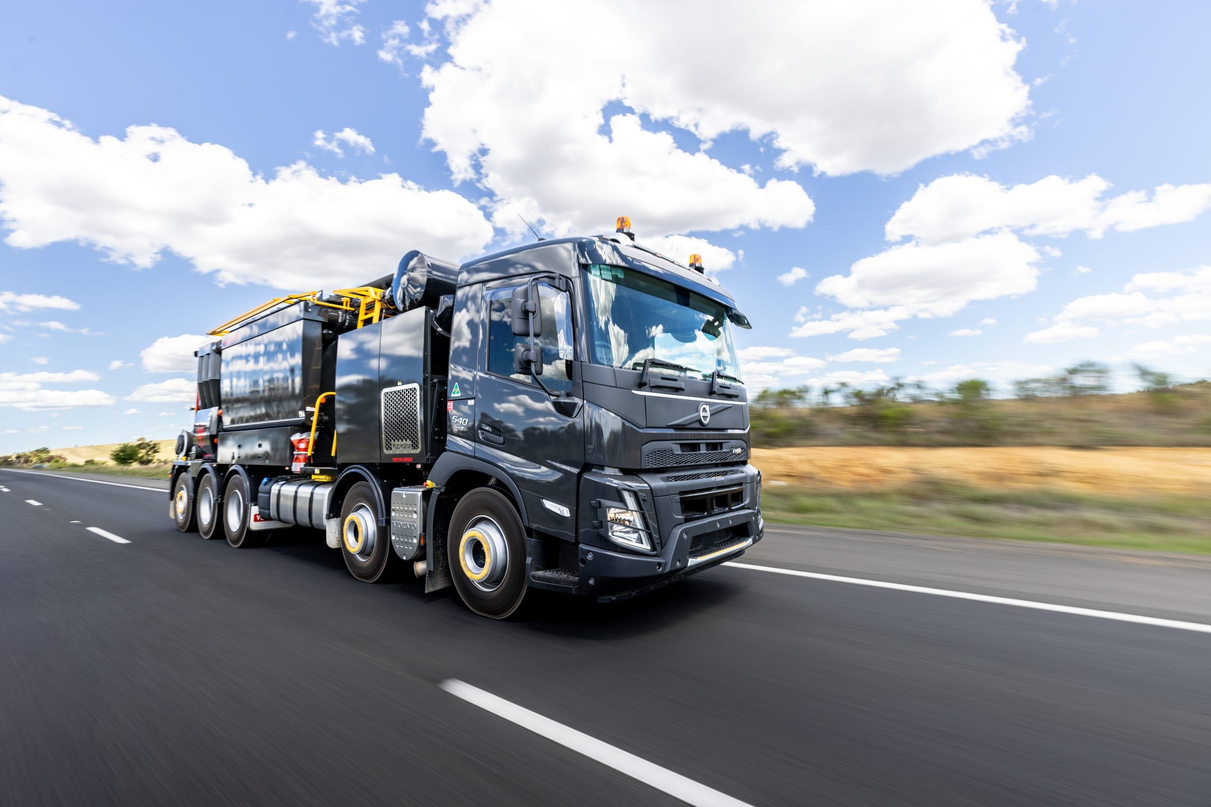 The HD 10-90 driving along a highway under a bright sky with scattered clouds.